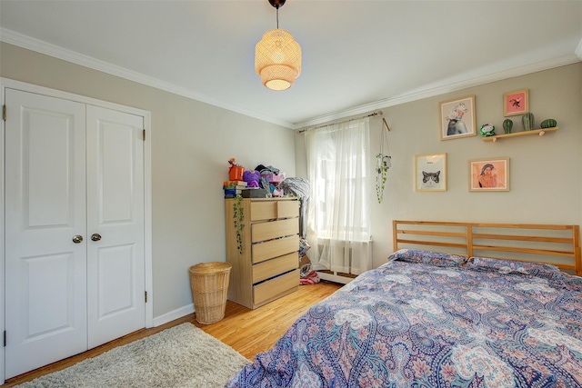 bedroom with ornamental molding, a closet, wood finished floors, and baseboards