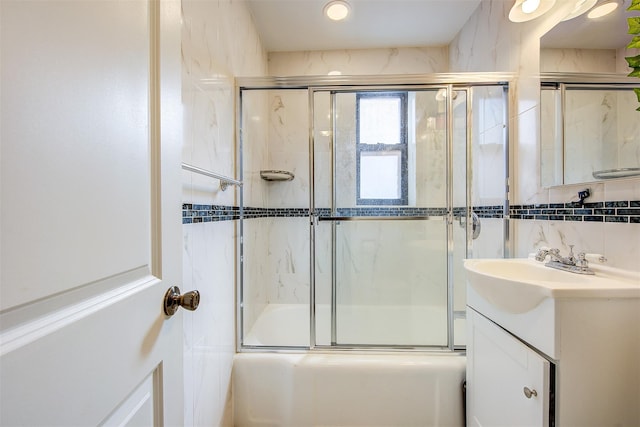 bathroom with enclosed tub / shower combo, tasteful backsplash, vanity, and tile walls