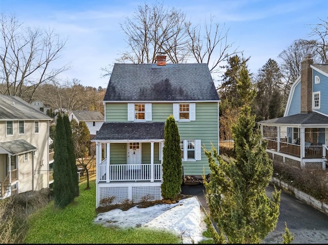 view of front of property with a chimney, covered porch, driveway, and a shingled roof