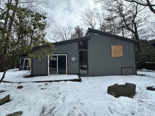 snow covered property featuring a garage and board and batten siding