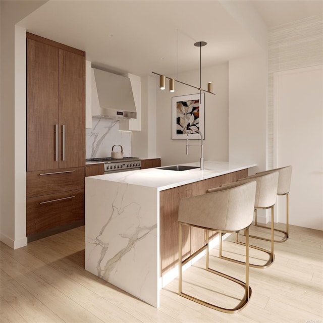 bar featuring light wood-type flooring, wall chimney range hood, backsplash, and a sink