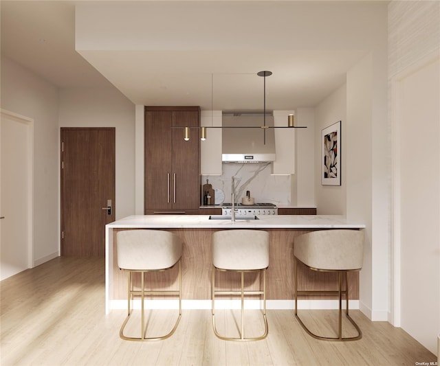 kitchen featuring tasteful backsplash, light wood-style flooring, a kitchen breakfast bar, a peninsula, and light countertops