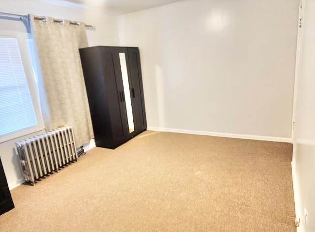 carpeted empty room with baseboards and radiator heating unit