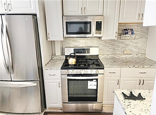 kitchen featuring stainless steel appliances, decorative backsplash, and white cabinets