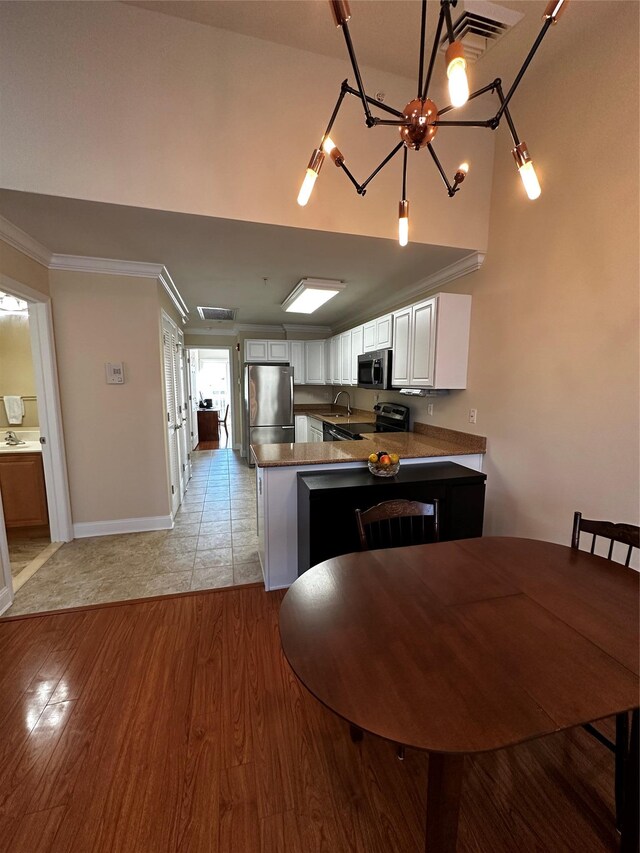 kitchen with stainless steel appliances, light wood-type flooring, a peninsula, and crown molding