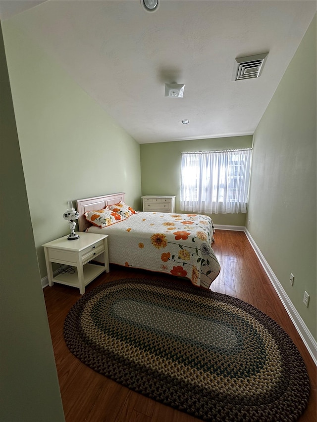 bedroom with visible vents, baseboards, and wood finished floors