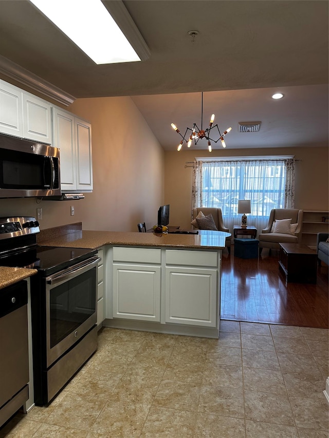 kitchen featuring open floor plan, stainless steel appliances, a peninsula, and white cabinetry