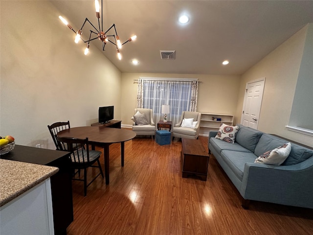 living room featuring vaulted ceiling, a notable chandelier, wood finished floors, and visible vents