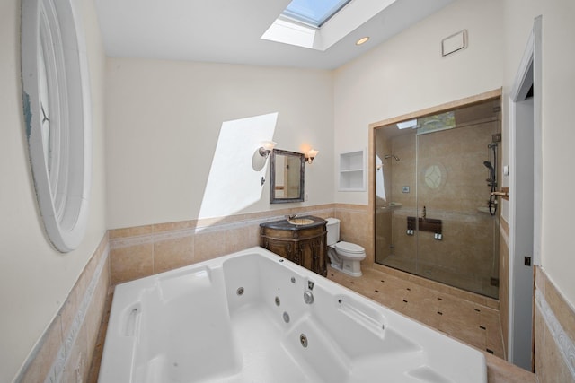 full bathroom with vanity, toilet, a tub with jets, lofted ceiling with skylight, and a shower stall
