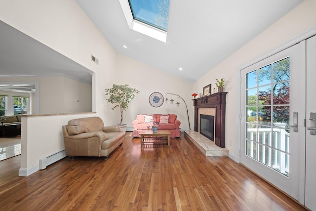 living room with a glass covered fireplace, baseboard heating, wood-type flooring, and visible vents
