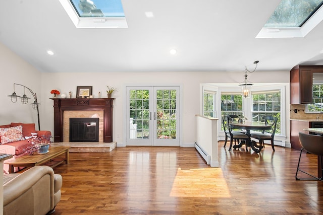 living room featuring wood finished floors, a fireplace, recessed lighting, a baseboard heating unit, and a skylight