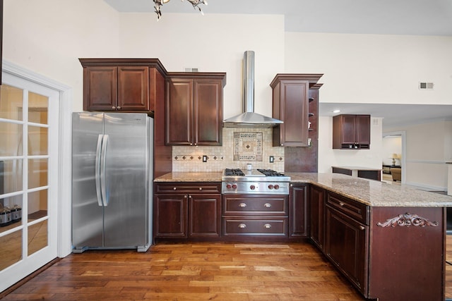 kitchen with visible vents, light wood-style floors, wall chimney exhaust hood, tasteful backsplash, and stainless steel appliances