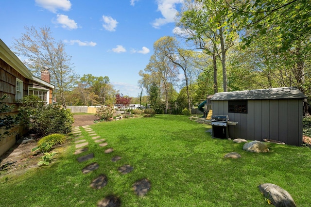 view of yard featuring a storage unit, fence, and an outbuilding