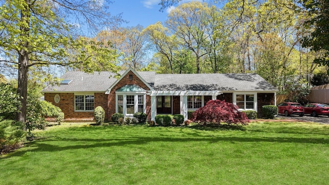 view of front facade with fence, roof with shingles, and a front lawn