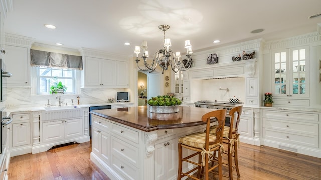 kitchen featuring light wood-style floors, a kitchen island, white cabinetry, and a sink