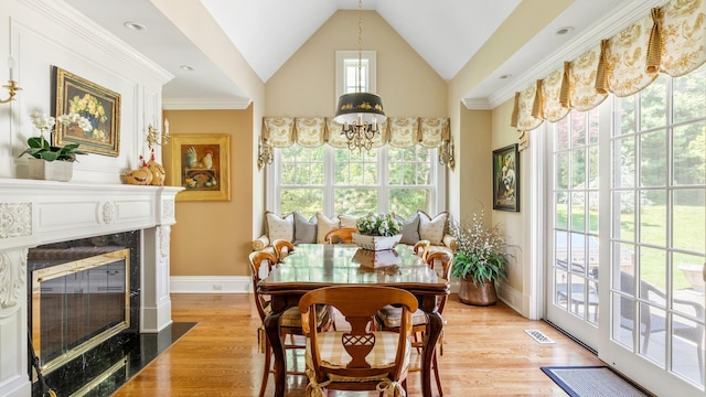 dining room featuring a chandelier, a premium fireplace, light wood-type flooring, and baseboards