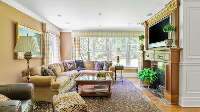 living area featuring recessed lighting, a premium fireplace, ornamental molding, wood finished floors, and baseboards