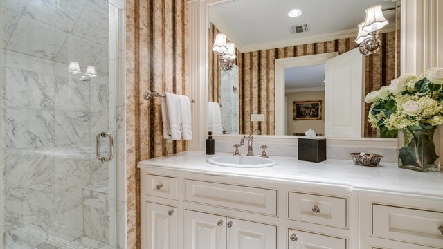 bathroom with a marble finish shower, visible vents, ornamental molding, vanity, and wallpapered walls