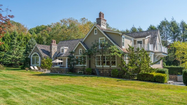 back of property featuring a yard, a chimney, and a balcony