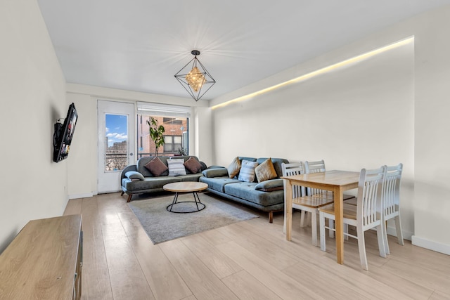 living room with baseboards, light wood finished floors, and an inviting chandelier