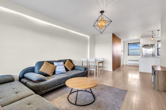 living room featuring light wood finished floors, radiator heating unit, and an inviting chandelier