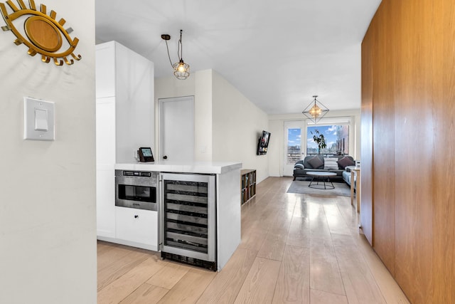 4705 Henry Hudson Pkwy W Unit 7G, Bronx, NY 10471 - bar featuring light wood-type flooring, beverage cooler, stainless steel oven, and hanging light fixtures