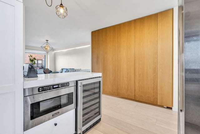 4705 Henry Hudson Pkwy W Unit 7G, Bronx, NY 10471 - kitchen with light wood-style flooring, beverage cooler, light countertops, hanging light fixtures, and freestanding refrigerator