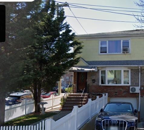 view of front of home featuring a garage, a fenced front yard, and brick siding