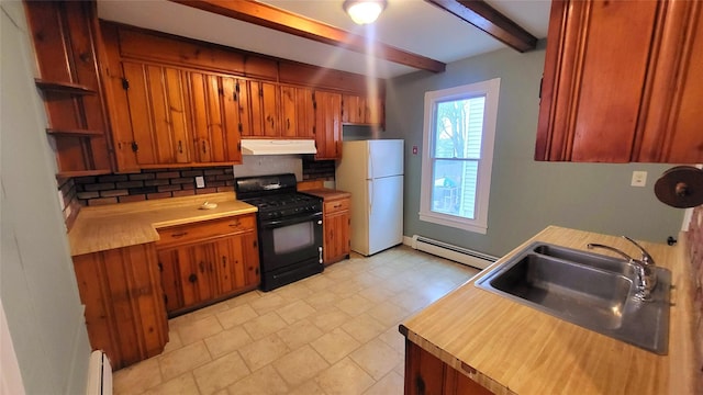 kitchen with a baseboard radiator, freestanding refrigerator, black gas stove, a sink, and under cabinet range hood