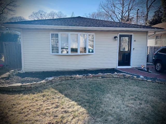 single story home with roof with shingles, a front yard, and fence