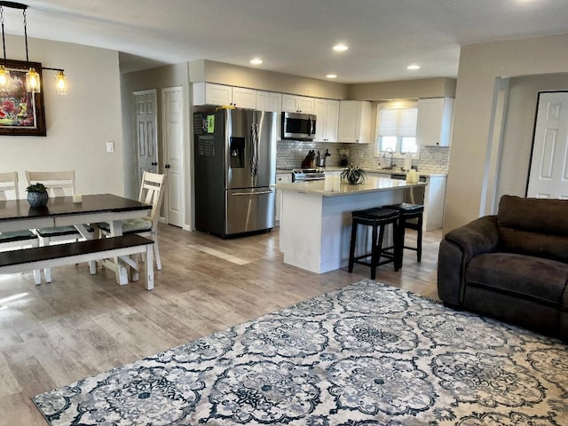 kitchen featuring tasteful backsplash, appliances with stainless steel finishes, white cabinetry, and light wood-type flooring