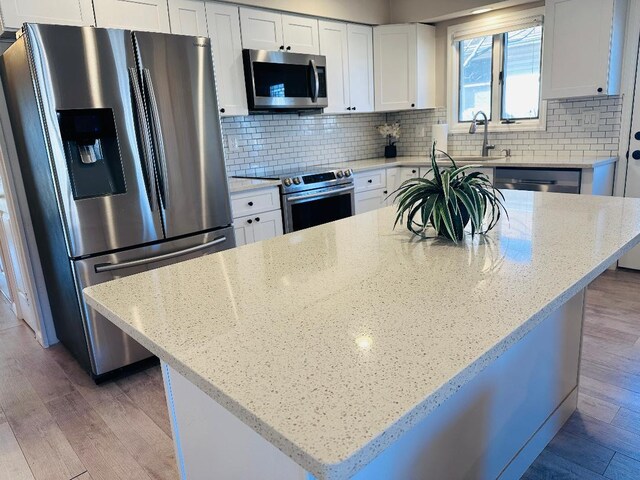 kitchen with light wood-style floors, backsplash, and stainless steel appliances