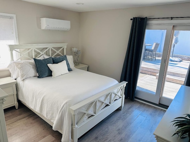 bedroom with multiple windows, a wall mounted air conditioner, and wood finished floors