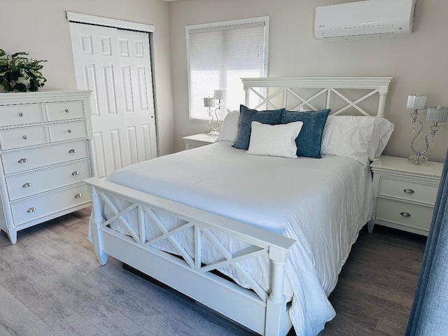 bedroom featuring a wall unit AC, wood finished floors, and a closet