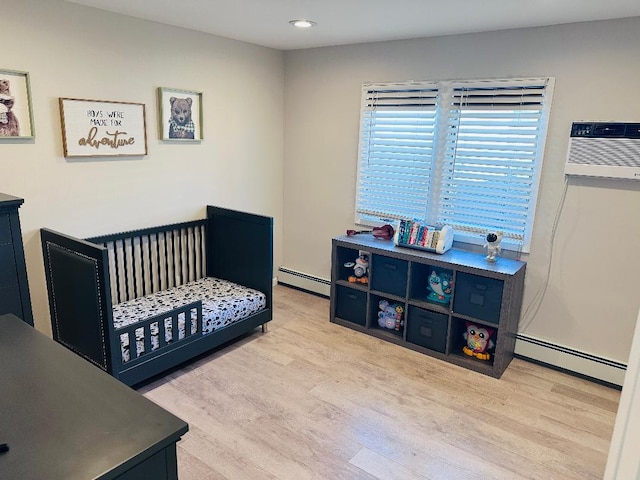 bedroom featuring wood finished floors, baseboard heating, and a wall mounted AC