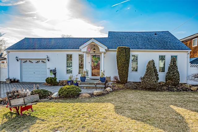 view of front of house with a garage, a shingled roof, decorative driveway, and a front yard