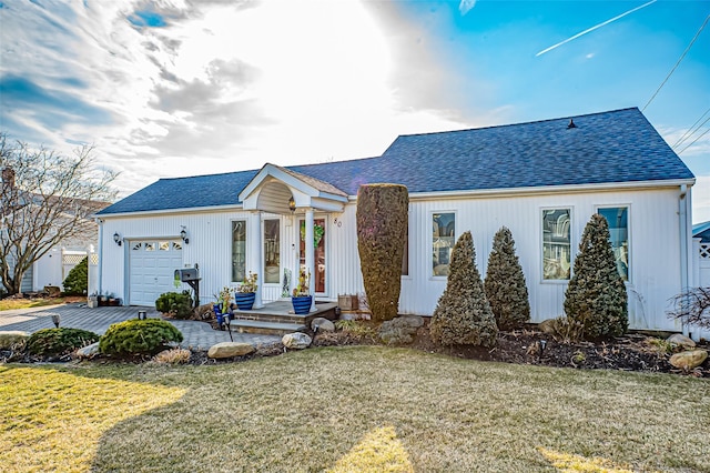 view of front of home featuring a shingled roof, a front yard, and an attached garage