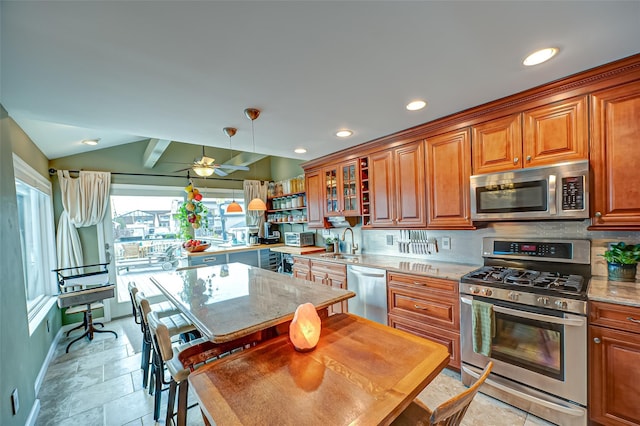 kitchen with tasteful backsplash, lofted ceiling, appliances with stainless steel finishes, brown cabinetry, and a sink