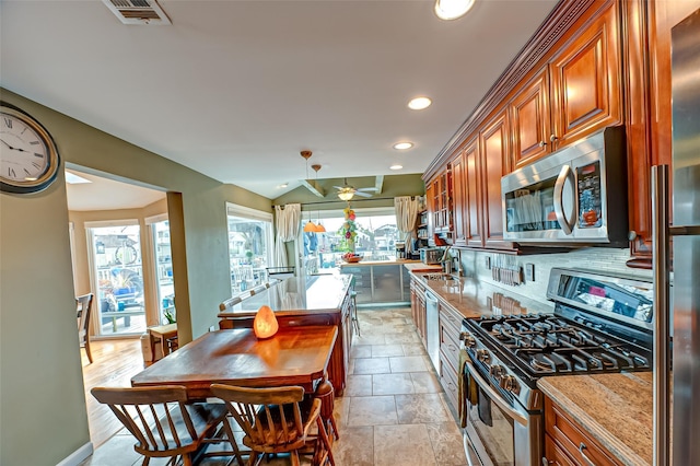 kitchen featuring stainless steel appliances, tasteful backsplash, brown cabinetry, and visible vents