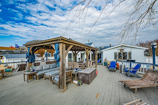 wooden deck featuring a gazebo, outdoor lounge area, and an outbuilding