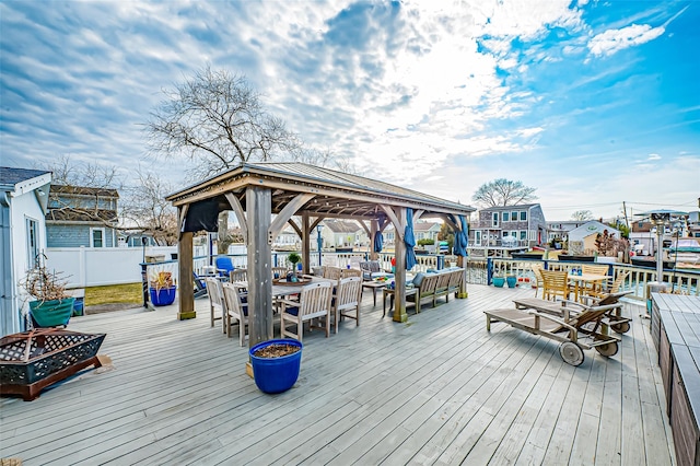 wooden terrace featuring outdoor dining space, fence, a fire pit, and a gazebo