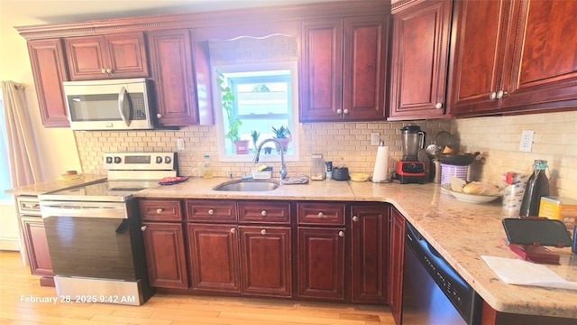 kitchen featuring stainless steel appliances, a sink, light stone counters, and dark brown cabinets