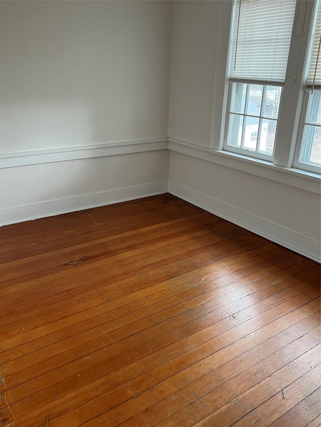 unfurnished room with hardwood / wood-style floors and baseboards