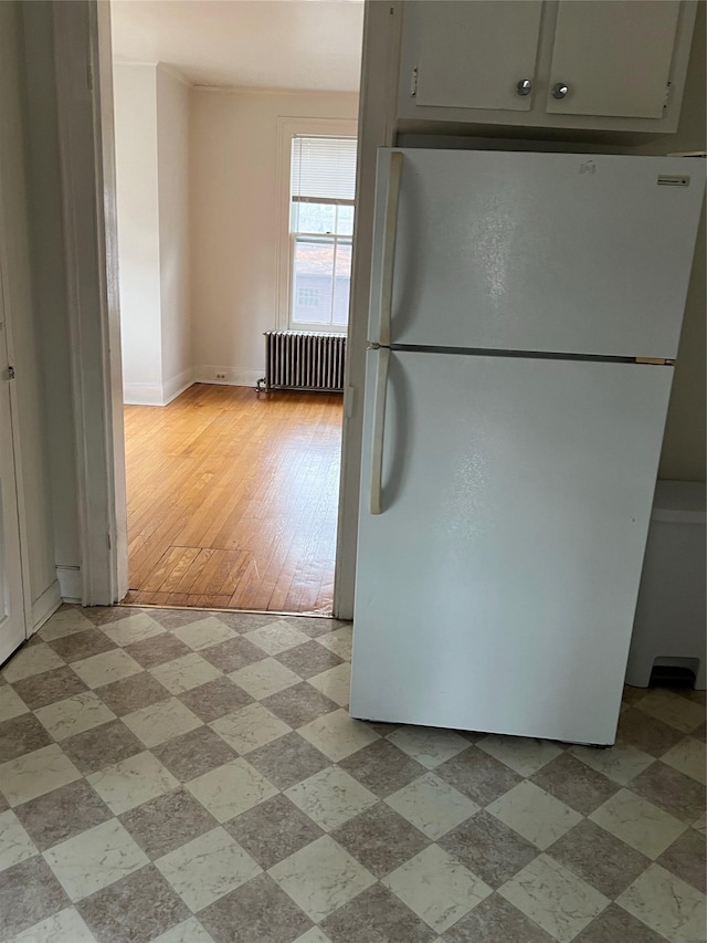 kitchen featuring light floors, radiator heating unit, baseboards, and freestanding refrigerator