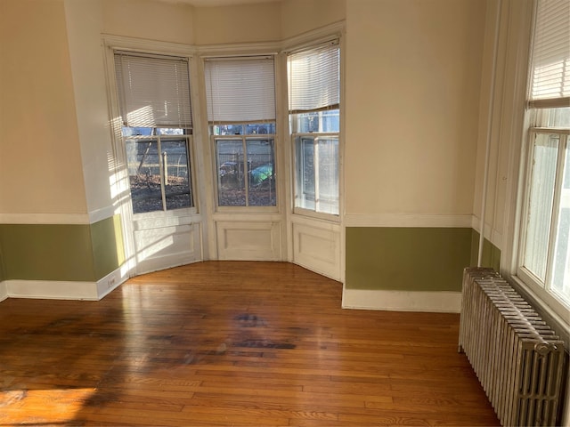 spare room with radiator, hardwood / wood-style flooring, and baseboards