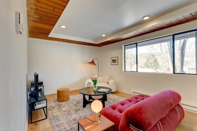 living area with recessed lighting, a raised ceiling, baseboards, and wood finished floors