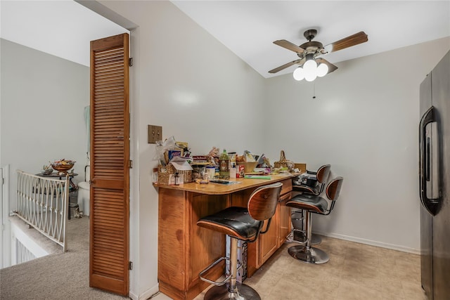 bar featuring a dry bar, baseboards, a ceiling fan, and freestanding refrigerator