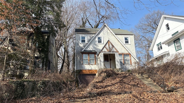 tudor home with an attached garage and roof with shingles