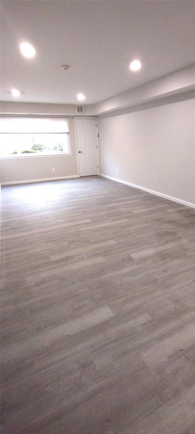 basement featuring baseboards, visible vents, and wood finished floors