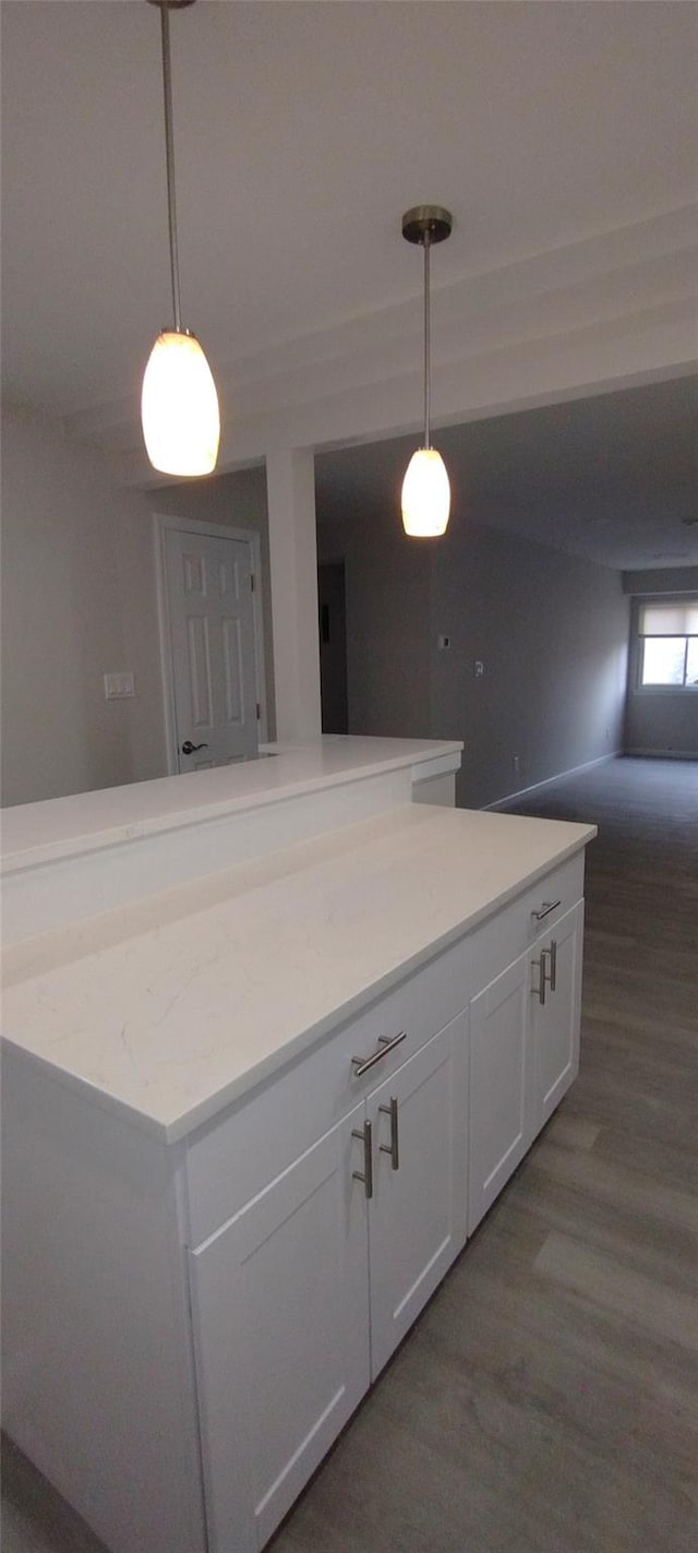 kitchen featuring white cabinetry, open floor plan, wood finished floors, and decorative light fixtures